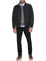 Campera bomber Tommy Hilfiger negra de poliéster, con cuello alto, cierre frontal con cremallera, dos bolsillos laterales con cremallera, puños elásticos y logo bordado en el pecho.