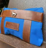 Sobre tipo cartuchera de lona con estampado de camuflaje y terminaciones en cuero marrón.