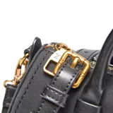 Cartera tipo baúl compacta de la marca XL, color negro, con material exterior de símil gamuza combinado con PU liso. Cuenta con un compartimento principal con cierre superior, bolsillo interno con cierre, doble asa corta rígida y correa larga regulable y desmontable. Los herrajes son metálicos en color dorado y tiene un detalle frontal con el logo XL metalizado.