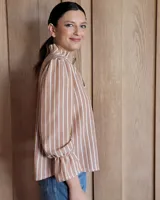 Blusa de algodón color azul, de corte suelto, con mangas largas abullonadas y cuello con volados y escote en V.