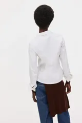 Camisa blanca de corte entallado con cuello clásico, cierre frontal de botones, mangas largas con puños abotonados y pinzas frontales y traseras para un ajuste estilizado.