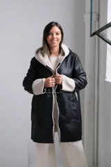 Tapado de cuero sintético negro con interior y detalles en corderito sintético color crema. Presenta capucha, cierre frontal y mangas largas con puños vueltos.