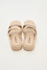 Sandalia de plataforma plana color beige, con dos tiras anchas en el empeine, una de ellas con hebilla metálica ajustable.