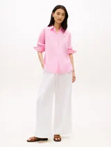Camisa de lino puro de corte amplio color rosado, con cuello inglés, mangas largas con puños abotonados, bajo camisero y logo bordado en el pecho.