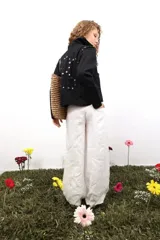 Pantalón de lino blanco de corte amplio y tiro medio-bajo. Presenta bolsillos laterales y traseros, cierre con botón metálico grabado y detalles de bordados laterales y traseros.