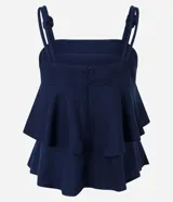 Blusa femenina color azul marino, sin mangas, con breteles anchos que tienen nudos decorativos y escote recto. Presenta capas sobrepuestas en la parte delantera que crean un leve volumen.