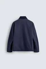 Cazadora de corte relajado color azul marino, confeccionada en algodón con estructura canvas y acolchado interior. Presenta cuello de solapa en pana combinada, mangas largas, bolsillos de plastrón con solapa en la cadera y cierre frontal de cremallera oculta con alamares metálicos.