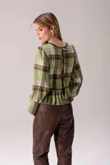 Blusa de manga larga confeccionada en tartán con estampado a cuadros en tonos marrones, blancos y mostaza. Presenta detalles en cuero marrón y cuello alto con corderito sintético.