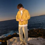 Camisa tipo overshirt de pana color mostaza, con cierre frontal de botones metálicos, dos bolsillos frontales con solapa y manga larga con puños abotonados.