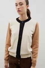 Saco de punto con diseño color block, presenta cuerpo en color bordó, mangas en color rojo y tapeta frontal con cuello redondo en color rosado. Posee cierre frontal con botones y puños acanalados.