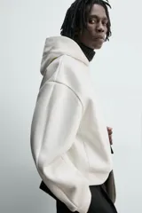 Sudadera tipo hoodie de corte boxy fit, confeccionada en tejido doble compacto de mezcla de algodón. Presenta cuello con capucha, manga larga y acabados en el mismo tejido.