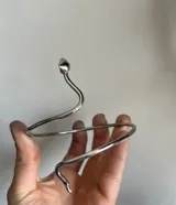 Brazalete rígido plateado con forma de serpiente enroscada.