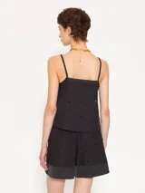 Top de poplin negro con breteles finos, escote recto y detalle de piedras decorativas al tono distribuidas en el frente y la espalda. Presenta terminaciones en satén en escote y aberturas laterales, con cierre invisible lateral.