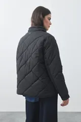 Campera acolchada de nylon color negro, con cuello alto, cierre frontal y botones a presión. Presenta un diseño de rombos y forro interior suave.