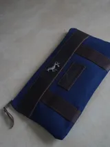 Sobre tipo cartuchera de lona con estampado de camuflaje y terminaciones en cuero marrón.