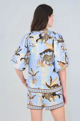 Short celeste con estampado de tigres y hojas, cintura elástica y bolsillos laterales.