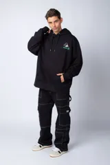 Buzo tipo canguro color negro con capucha y cordones ajustables. Presenta un pequeño estampado en el pecho con la silueta de Mickey Mouse y un detalle a cuadros en color verde.