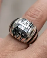 Anillo de acero de diseño bombé, con patrón geométrico esmaltado en tonos negro y gris oscuro.
