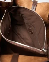 Cartera de mano tipo tote color marrón con textura símil cocodrilo, doble asa de hombro y detalles de tiras colgantes en los laterales.