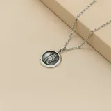 Conjunto compuesto por una cadena de eslabones y una medalla circular de San Expedito, ambos realizados en plata 925 con acabado envejecido.