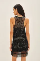 Vestido corto negro de calce recto, sin mangas y escote redondo. Confeccionado en tul bordado con piedras, lentejuelas, canutillos y flecos de mostacillas. Incluye un viso a tono con breteles finos.