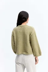 Saco de punto con textura tipo bouclé, de calce relajado y diseño levemente cropped. Cuenta con cuello redondo y cierre frontal mediante botones.