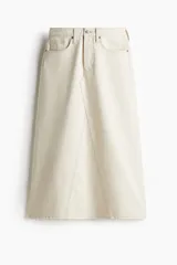 Pollera larga de denim de algodón rígido, color beige claro, con cinco bolsillos y tiro alto. Presenta cierre de botones y una silueta levemente evasé con nesgas delanteras y traseras.