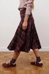 Falda midi de corte irregular con diseño a cuadros en tonos marrones, negros y beige. Presenta una silueta acampanada con caída fluida.