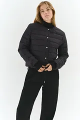 Campera acolchada negra, de nylon guateado, con cuello redondo y cierre frontal de botones a presión. Presenta bolsillos laterales discretos y elástico fino en los puños.