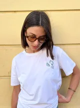 Remera blanca de manga corta con estampa gráfica en la espalda que ilustra una pescadería con el texto 'Fresco de hoy $1000'.