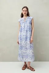 Vestido largo con estampado geométrico en tonos azul, marrón y beige. Tiene escote en V con lazos ajustables, mangas cortas y corte holgado.