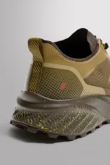 Zapatilla deportiva de trail running color beige con detalles en marrón. Presenta una parte superior de tejido técnico transpirable, refuerzos en puntera y talón, sistema de ajuste rápido con cordones técnicos y entresuela con tecnología de amortiguación y acabado moteado.