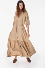 Vestido camisero largo de lino italiano color celeste, de corte relajado, con mangas caídas, jareta ajustable en la cintura, cierre frontal de botones y bajo con volado fruncido.