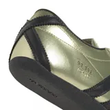 Championes Adidas modelo Tokyo, con acabado metalizado en color dorado y detalles en negro. Presenta las icónicas tres tiras laterales, cordones y suela de goma en color negro.