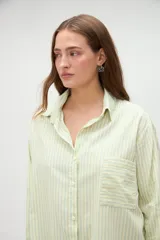 Camisa de manga larga de algodón, con diseño a rayas en tonos azules y morados, calce holgado, cuello camisero, cierre frontal con botones y un bolsillo aplicado en el pecho.