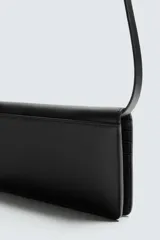 Cartera tipo bandolera de piel color marrón oscuro, con solapa y cierre a presión. Incluye seis ranuras para tarjetas, una ranura para billetes y un monedero interior con cierre de cremallera. Posee un asa de hombro ajustable y extraíble.