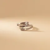 Anillo de plata 925 con acabado satinado, diseño abierto de líneas envolventes y dos circonias engastadas.