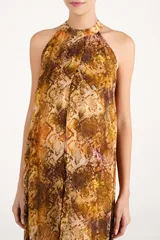 Vestido largo de viscosa con estampado animal print tipo serpiente en tonos tierra. Presenta un diseño fluido con cuello halter y abertura frontal, ideal para un look sofisticado.