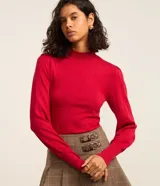 Suéter negro de punto con cuello alto, mangas largas abullonadas y puños largos.