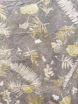 Mantel rectangular grande de algodón con estampado botánico en tonos dorados sobre fondo marrón.