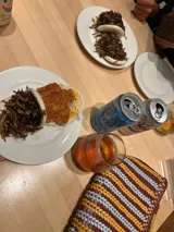 Cartera de mano tipo clutch, de cuero trenzado a mano en color negro y beige, con diseño de rayas verticales.