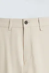 Pantalón chino de corte slim fit, confeccionado en tejido elástico. Presenta bolsillos frontales, bolsillos traseros de vivo con botón y cierre frontal con cremallera y botón.