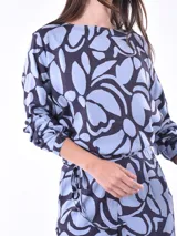 Blusa de mangas largas con estampado de hojas en tonos celeste y azul marino, con lazo en la cintura.