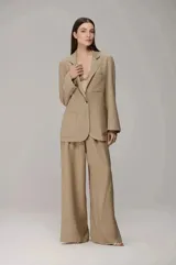 Conjunto de sastrería color beige, compuesto por un blazer oversize de botonadura simple con bolsillos frontales amplios y un pantalón de corte recto y holgado.