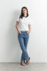 Remera blanca de manga corta con cuello polo azul marino y cierre metálico.