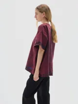 T-shirt de denim color bordó con efecto washed, corte oversize y cuello redondo. Presenta un estampado de tres estrellas azules en el pecho y la palabra "PASTIK" en azul en el bajo.