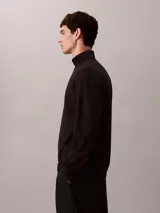 Remera de manga larga con cuello alto tipo tortuga, confeccionada en tejido de punto ponte. Presenta un diseño minimalista con logo de la marca bordado discretamente en el cuello.