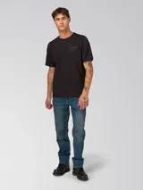 Remera de algodón de corte clásico y cuello redondo, color negro. Presenta un diseño minimalista con un pequeño gráfico bordado en el pecho y un parche de la marca en la manga izquierda.