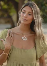 Collar de alpaca con dije grande en forma de hoja de ginkgo biloba, colgado de un aro rígido y fino al cuello.