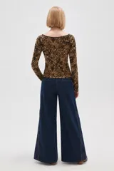 Remera de manga larga con cuello bote, confeccionada en tejido con estampado animal print. Presenta un ajuste al cuerpo y un borde en color negro en el escote.
